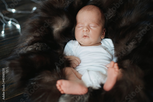 newborn is sleeping peacefully on a fur blanket.