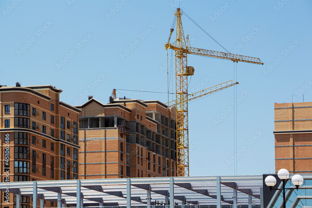 Tower crane and reinforced building under construction project site against blue sky. Tower crane and reinforced building under construction project site against blue sky.