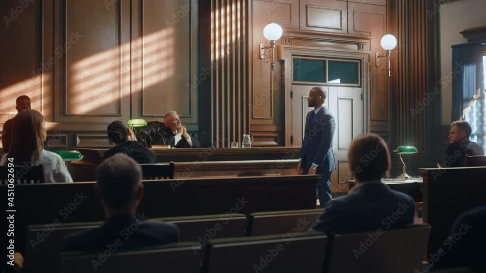 Court of Law Trial in Session: Portrait of Charismatic Male Public Defender Making Touching, Passionate Speech to Judge and Jury. Attorney Lawyer Protecting Client, Presenting Case. Court of Law Trial in Session: Portrait of Charismatic Male Public Defender Making Touching, Passionate Speech to Judge and Jury. Attorney Lawyer Protecting Client, Presenting Case.