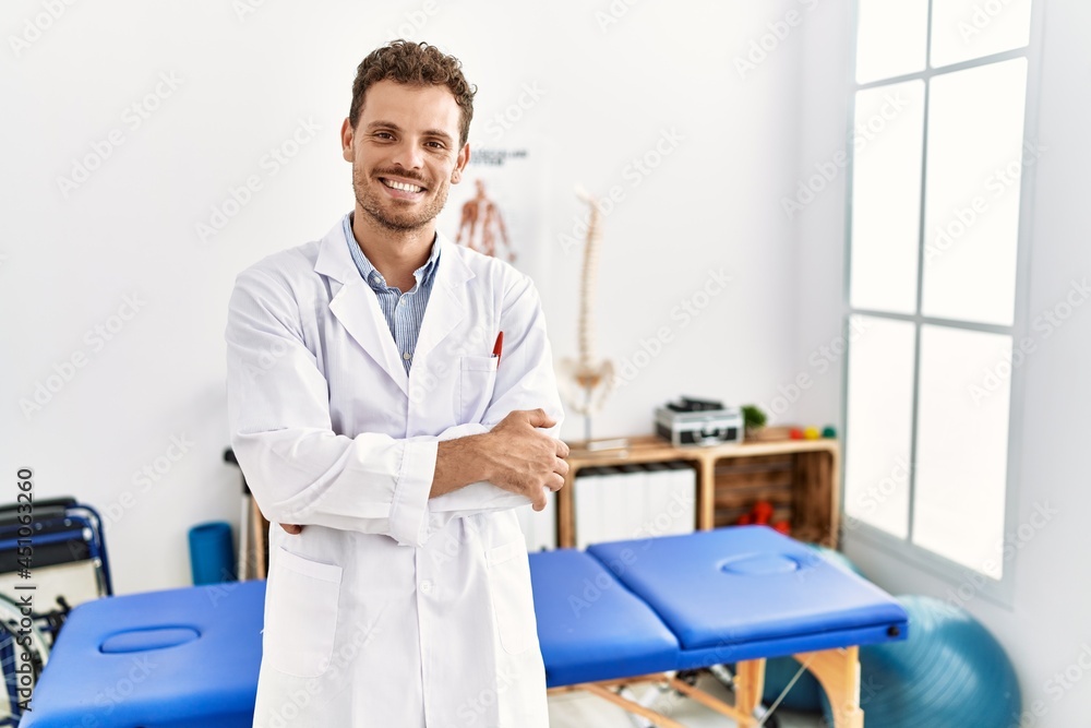 Handsome young man working at pain recovery clinic happy face smiling with crossed arms looking at the camera. positive person. Handsome young man working at pain recovery clinic happy face smiling with crossed arms looking at the camera. positive person.