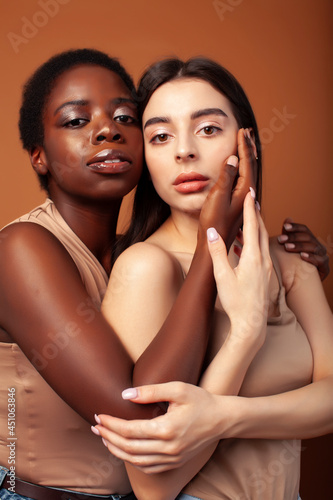 young pretty asian, afro woman posing cheerful together on brown background, lifestyle diverse nationality people concept