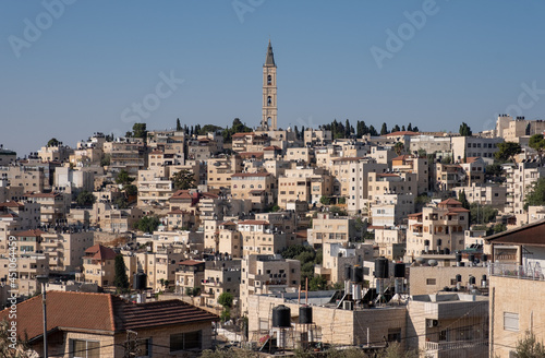 64 meters "Russian candle" bell tower of the Russian church, located in the Mount of Olives Ascension Monastery compound. Famous landmark of Jerusalem. The Arab village At-Tur on the foreground.