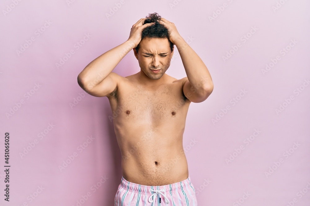 Fototapeta premium Young handsome man wearing swimwear shirtless suffering from headache desperate and stressed because pain and migraine. hands on head.