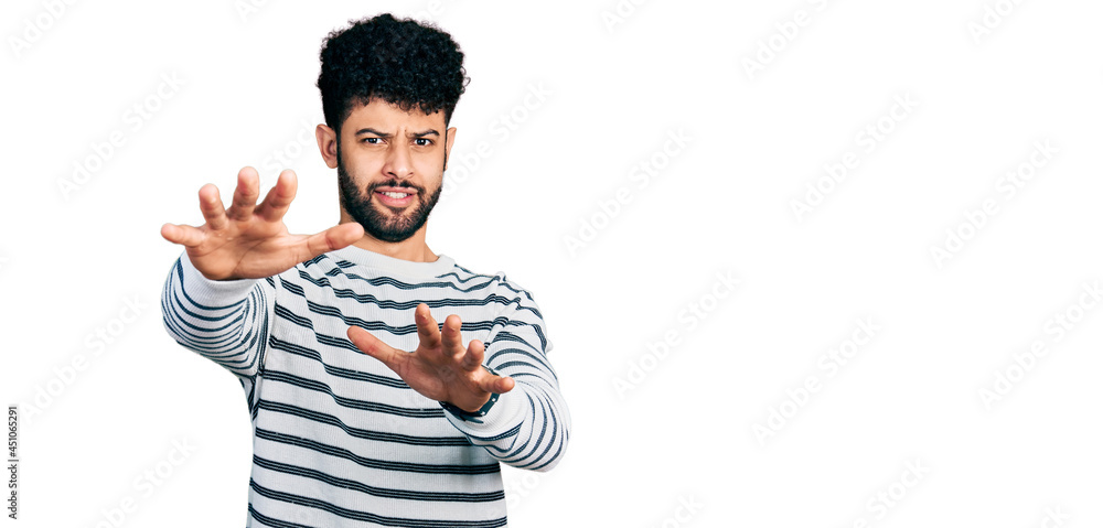 Fototapeta premium Young arab man with beard wearing casual striped sweater afraid and terrified with fear expression stop gesture with hands, shouting in shock. panic concept.