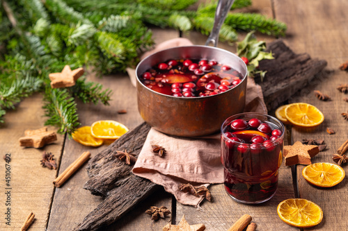  Hot mulled red wine drink with citrus, apples, cinnamon sticks, cloves and anise in cooking pan on wooden background