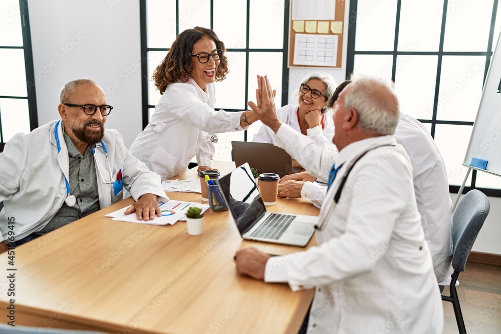 Group of middle age doctor smiling happy with hands united raised up at the clinic office.