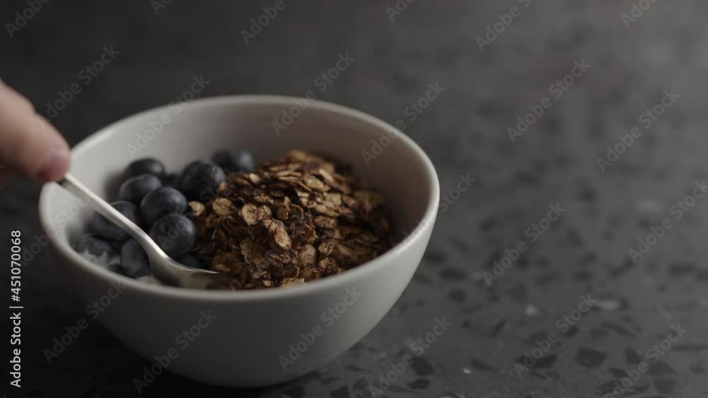 Slow motion man eat granola with yogurt and blueberries in white bowl Slow motion man eat granola with yogurt and blueberries in white bowl