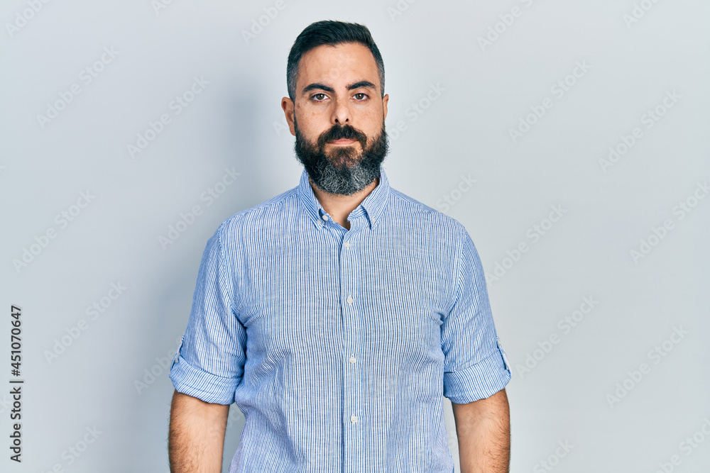 Young hispanic man wearing casual clothes with serious expression on face. simple and natural looking at the camera. Young hispanic man wearing casual clothes with serious expression on face. simple and natural looking at the camera.