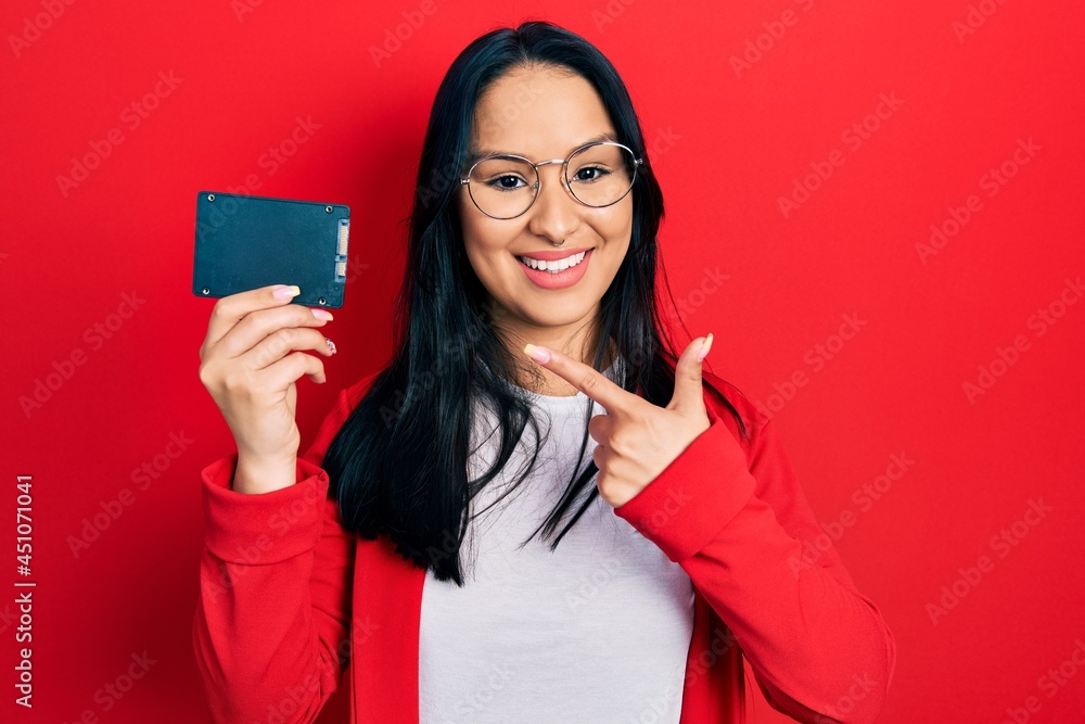 Naklejka premium Beautiful hispanic woman with nose piercing holding ssd memory smiling happy pointing with hand and finger