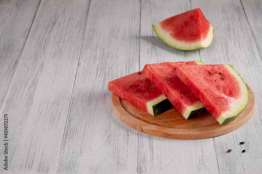 Close-up of sliced pieces of ripe red watermelon on a light wooden surface. Healthy food concept, summer food. Selective focus.