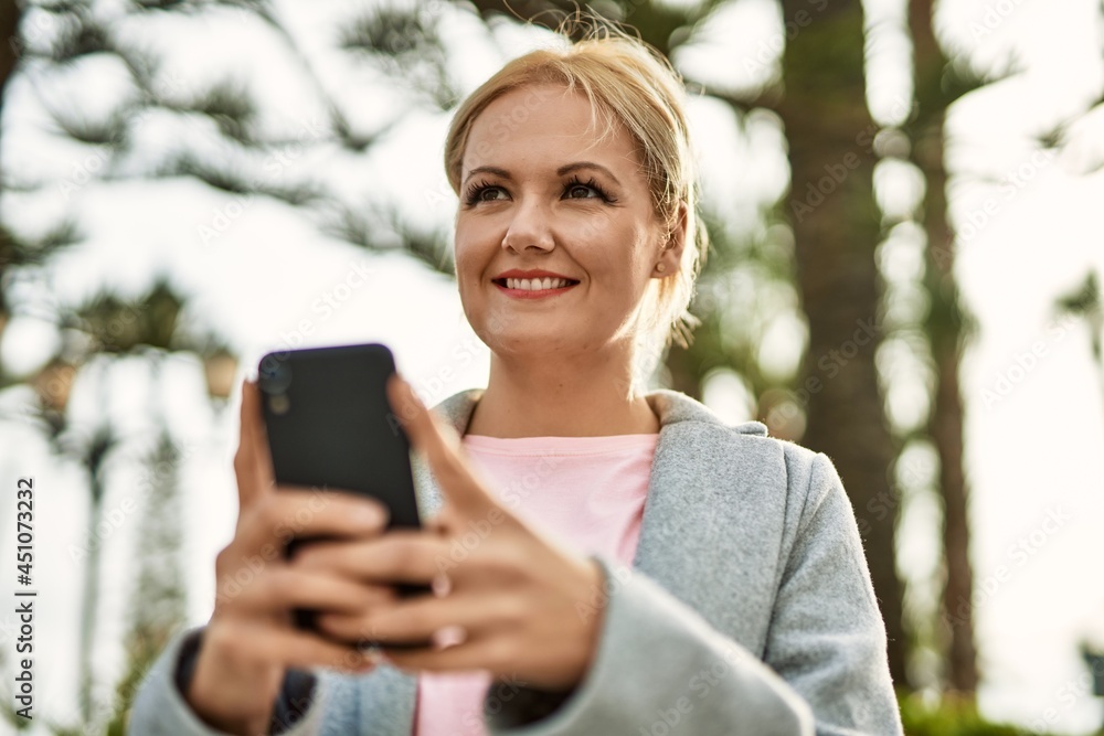 Young blonde businesswoman smiling happy using smartphone at the city.