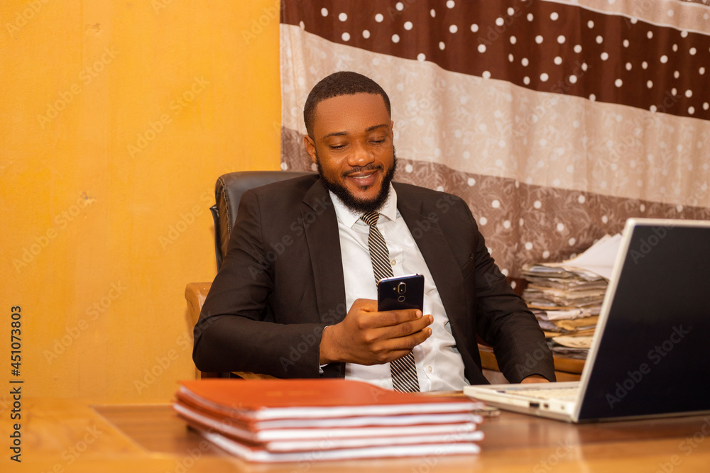 handsome african business man going through his phone in the office