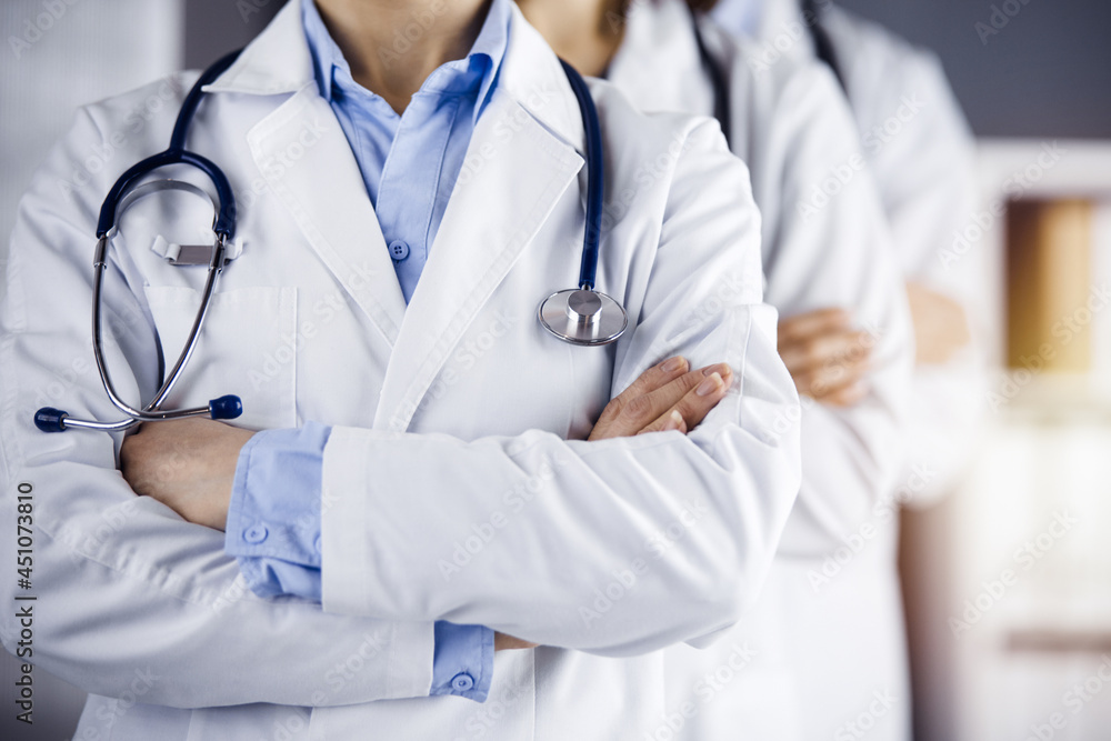 Group of modern doctors standing as a team with arms crossed in sunny hospital and ready to help patients. Medical help, insurance in health care Group of modern doctors standing as a team with arms crossed in sunny hospital and ready to help patients. Medical help, insurance in health care