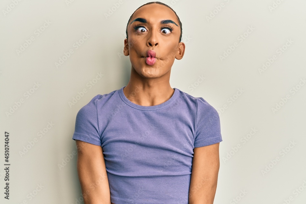 Hispanic man wearing make up and long hair wearing casual t shirt making fish face with lips, crazy and comical gesture. funny expression. Hispanic man wearing make up and long hair wearing casual t shirt making fish face with lips, crazy and comical gesture. funny expression.