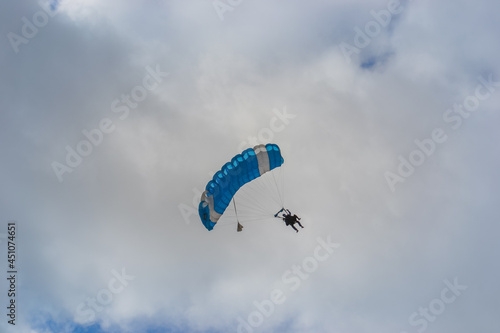 Skydiving as an exciting but extreme sport. People descend on blue parachutes