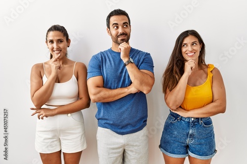 Group of young hispanic people standing over isolated background with hand on chin thinking about question  pensive expression. smiling and thoughtful face. doubt concept.