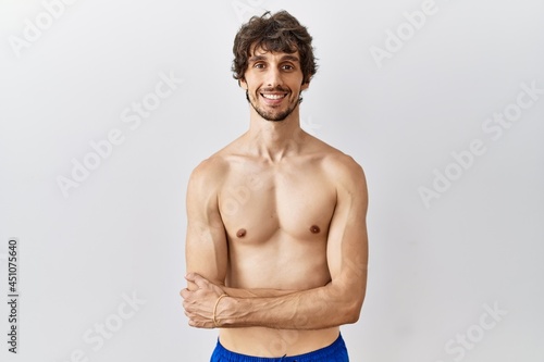 Young hispanic man standing shirtless over isolated, background happy face smiling with crossed arms looking at the camera. positive person.