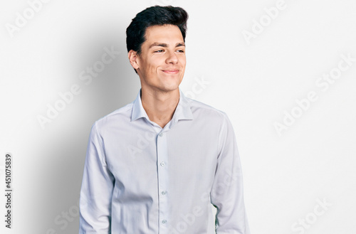 Young hispanic business man wearing business clothes smiling looking to the side and staring away thinking.
