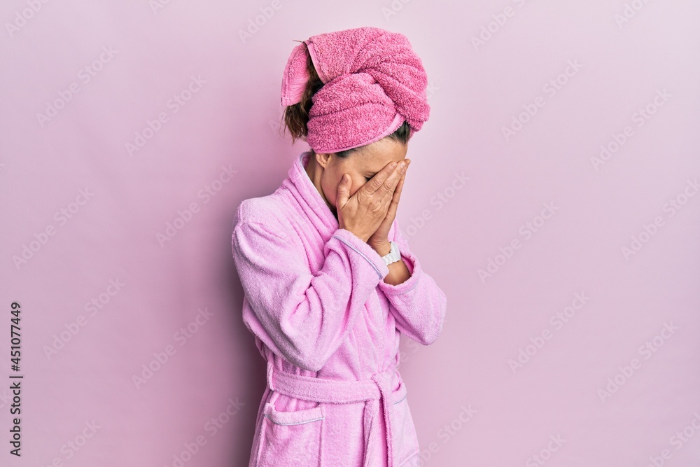 Young blonde woman wearing shower towel cap and bathrobe with sad expression covering face with hands while crying. depression concept. Young blonde woman wearing shower towel cap and bathrobe with sad expression covering face with hands while crying. depression concept.