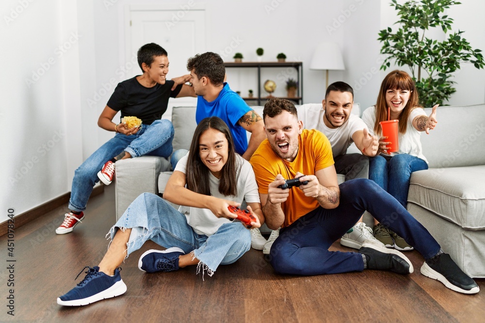 Fototapeta premium Group of young friends smiling happy playing video game at home.