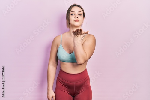 Young hispanic girl wearing sportswear looking at the camera blowing a kiss with hand on air being lovely and sexy. love expression.
