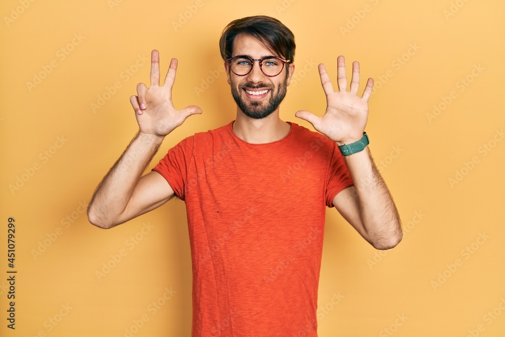 Naklejka premium Young hispanic man wearing casual clothes and glasses showing and pointing up with fingers number eight while smiling confident and happy.