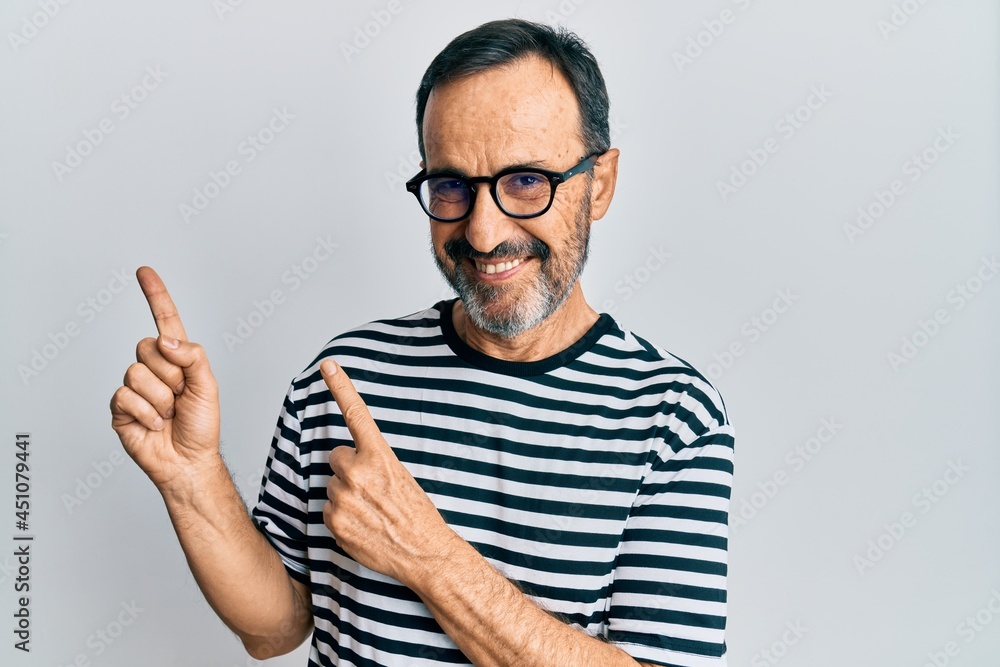 Fototapeta premium Middle age hispanic man wearing casual clothes and glasses smiling and looking at the camera pointing with two hands and fingers to the side.