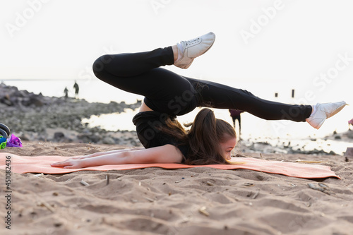 Girl gymnast trains on the beach by the sea. Photo series