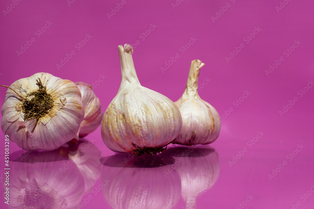 Obraz premium Four heads of garlic lie on a purple background. 