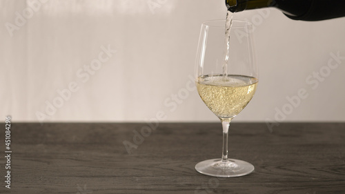 Bilde på lerret Pour white whine in wine glass on oak table