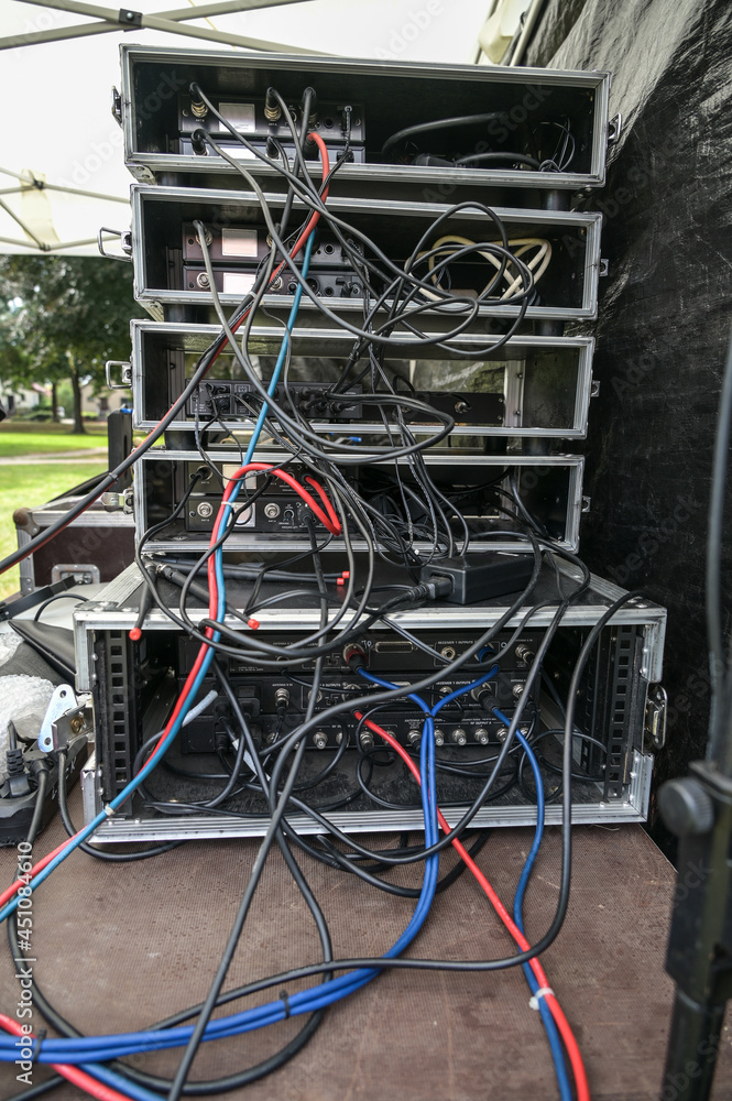 Cabling in multiple flight case racks with amplifier, effect devices, and radio microphone system on the desk of the sound mixer an open air music festival, selected focus Cabling in multiple flight case racks with amplifier, effect devices, and radio microphone system on the desk of the sound mixer an open air music festival, selected focus