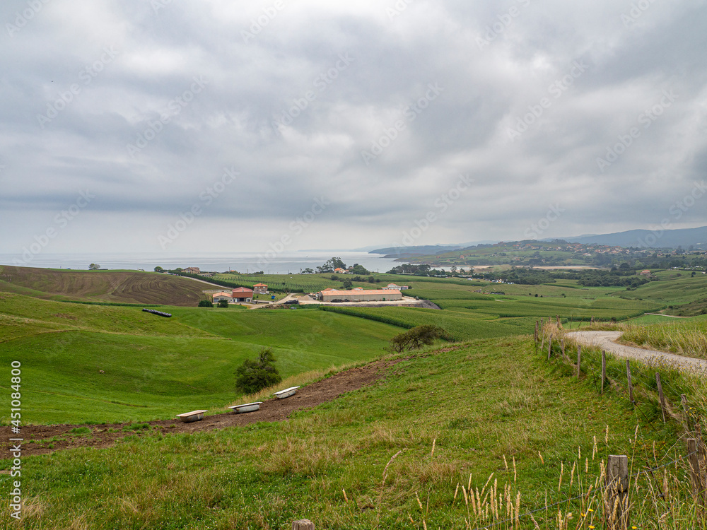 Vistas de paisaje  verde desde un sendero en Oyambre, con el mar y nubes al fondo, Cantabria, España, verano de 2020