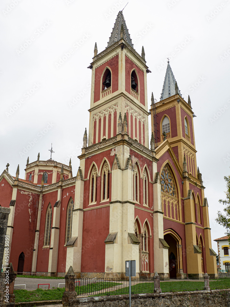 Vistas de la fachada roja y ocre de estilo neogótico de la Iglesia de San Pedro Advíncula, en Cobreces, Cantabria, verano de 2020