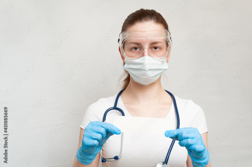 Female doctor with stethoscope in a mask, goggles, gloves holds a white sheet of paper in her hands. Covid-19 Female doctor with stethoscope in a mask, goggles, gloves holds a white sheet of paper in her hands. Covid-19