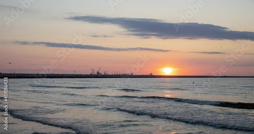 Landscape with sunrise on the Black Sea beach. The timelapse captures a boat with fishermen returning from the sea, and a lot of seagulls flying in search of fish and shells. photo