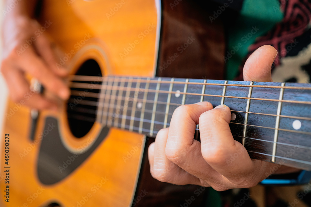 A person playing guitar. Partial view of a person with selective focus on the front hand.