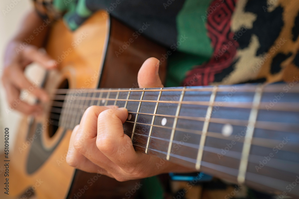 Fototapeta premium A person playing guitar with the front hand focused selectively