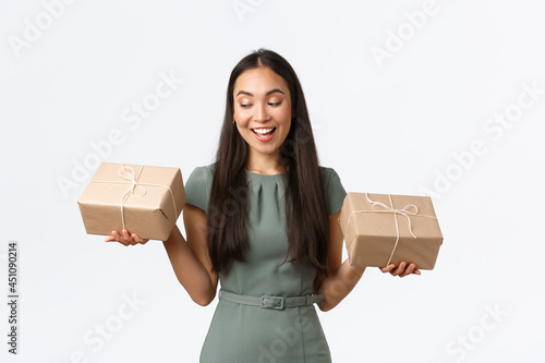 Small business owners, startup and work from home concept. Smiling successful store owner holding two boxes with orders, packing shipping items for clients, standing white background photo