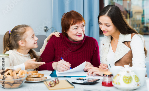 Portrait of friendly happy family sitting at home table, working with papers