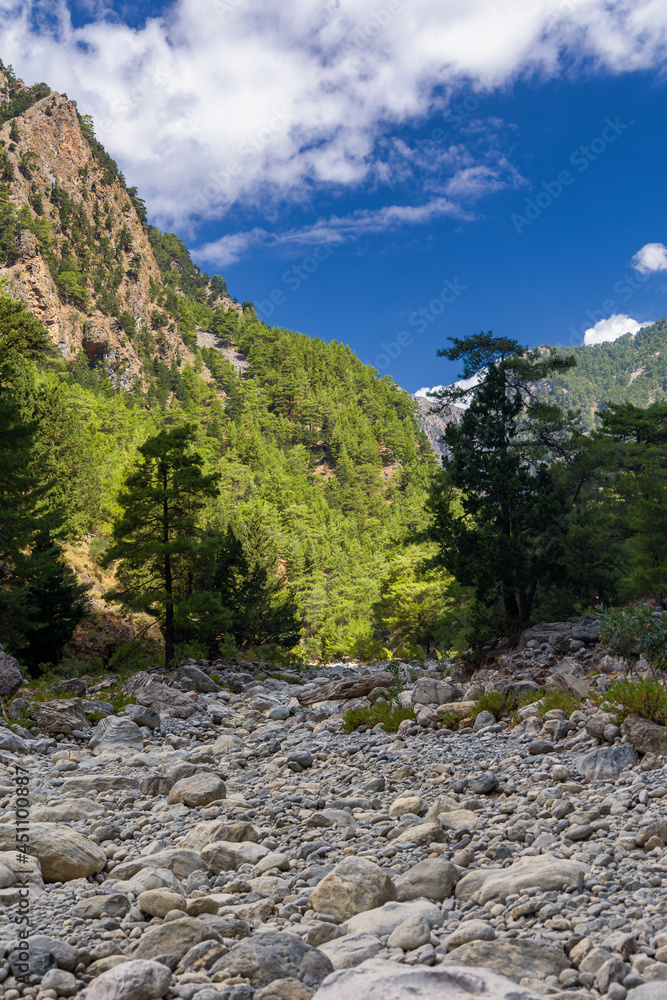 Dry riverbed and towering cliffs in a huge natural gorge (Samaria Gorge, Crete, Greece) Dry riverbed and towering cliffs in a huge natural gorge (Samaria Gorge, Crete, Greece)