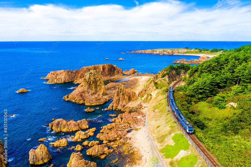 青森県 深浦町にある行合崎付近の奇岩沿いを走行するリゾート列車を俯瞰撮影	
