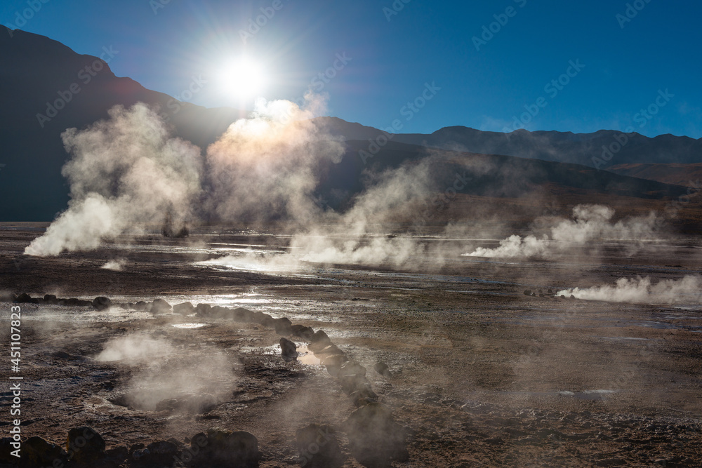 El Tatio geyser field landscape at sunrise with hot steam and sunbeam, Atacama Desert, Chile.