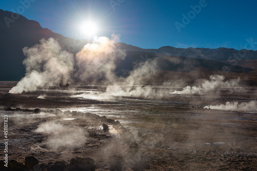 El Tatio geyser field landscape at sunrise with hot steam and sunbeam, Atacama Desert, Chile.