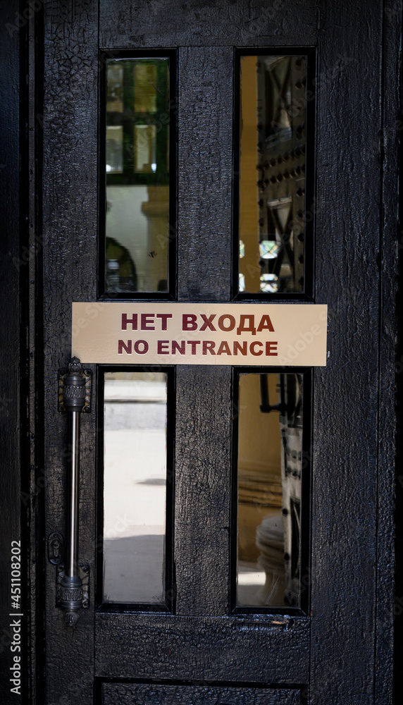 Black door with the inscription 'No Entrance' in Russian and English Black door with the inscription 'No Entrance' in Russian and English