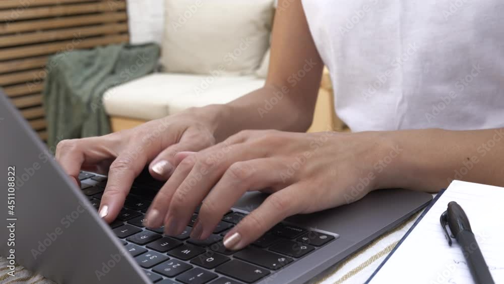 Female hands of woman working from home using her laptop in the garden on a sunny day Female hands of woman working from home using her laptop in the garden on a sunny day