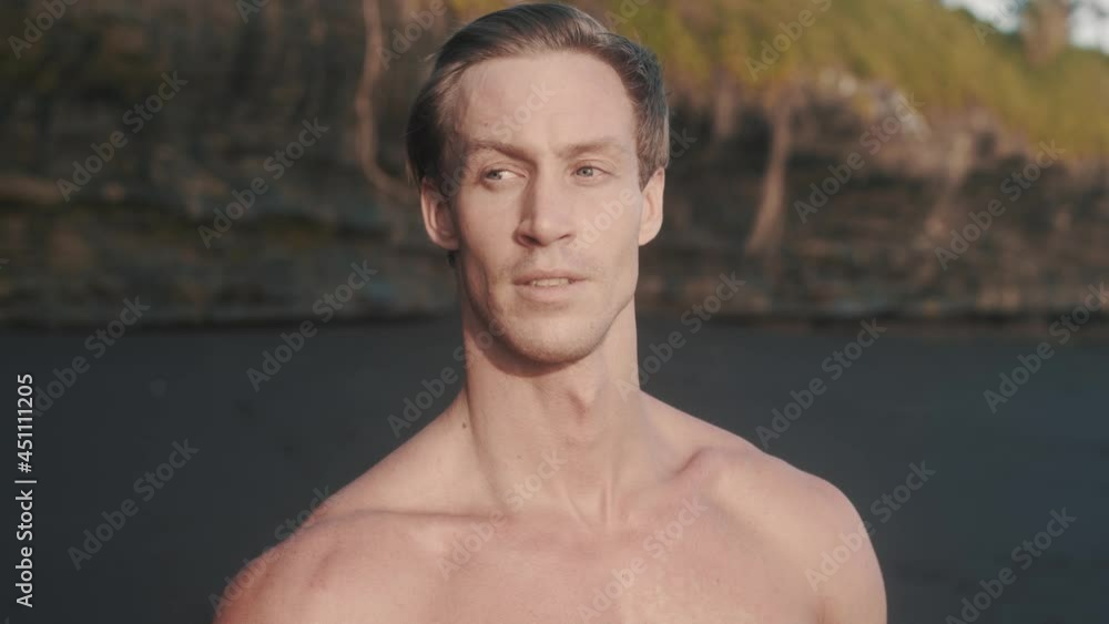 Portrait of young fitness Caucasian man looking around at the sea shore. Sportsman with perfect athletic body show his broad shoulders, masculine chin and wide neck. High quality 4k footage Portrait of young fitness Caucasian man looking around at the sea shore. Sportsman with perfect athletic body show his broad shoulders, masculine chin and wide neck. High quality 4k footage