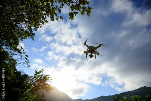 White drone with camera flying in summer mountains