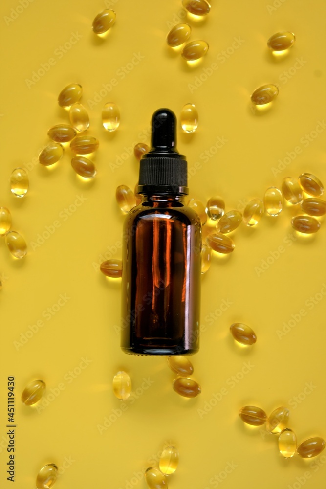 Vitamin D. Oil extract and gelatin capsules with vitamin D on a bright yellow background.Vitamins and minerals. Food supplements. Vitamin D. Oil extract and gelatin capsules with vitamin D on a bright yellow background.Vitamins and minerals. Food supplements.
