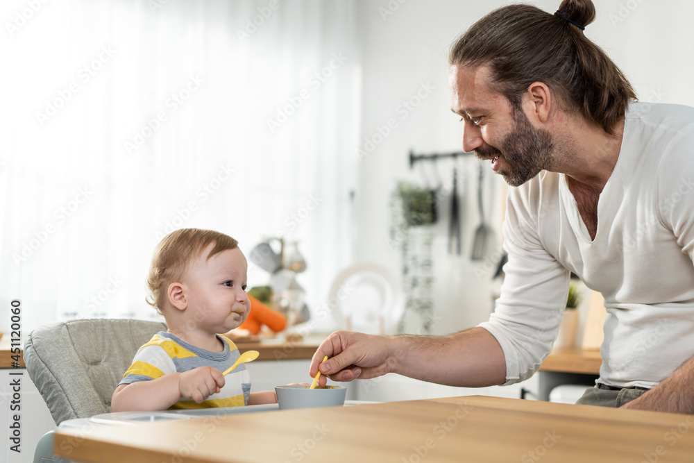 Caucasian attractive father take care of baby boy toddler in kitchen. Caucasian attractive father take care of baby boy toddler in kitchen.