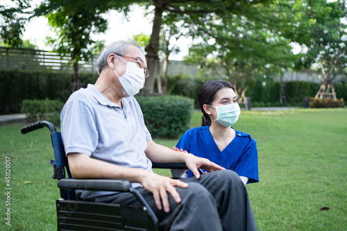 Asian nurse wear mask, support disabled senior elder man on wheelchair. 